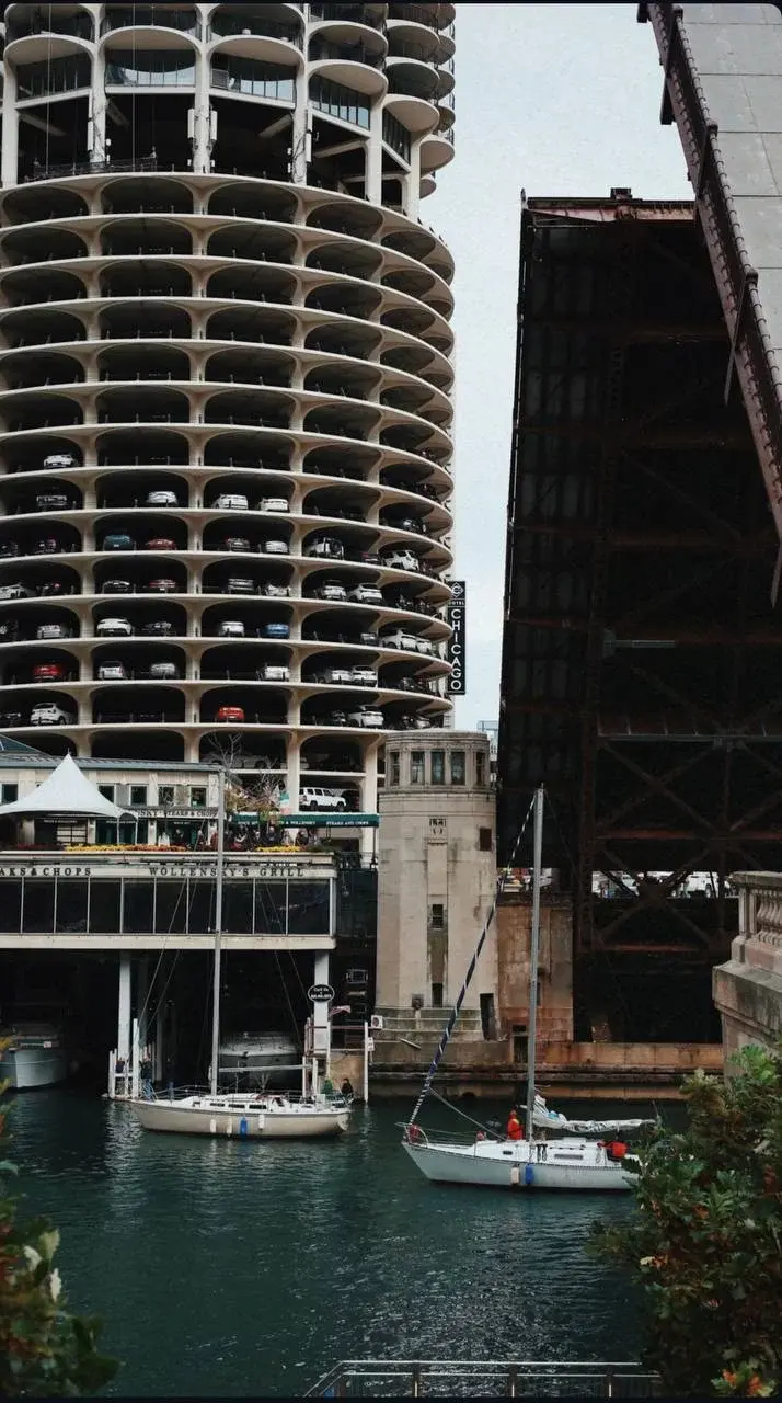 Sailboats on the Chicago River beneath Marina City's curved balconies and a raised bridge