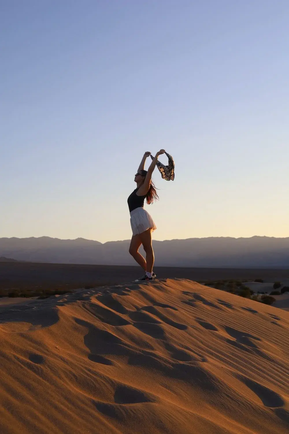 A person standing on sunlit sand dunes in Death Valley